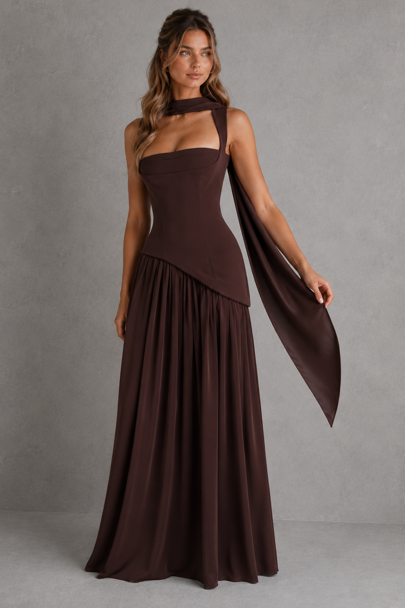 Woman wearing a brown halter neck dress with a draped fabric against a gray background