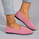 Pink slip-on shoes worn with light blue jeans on a gray background