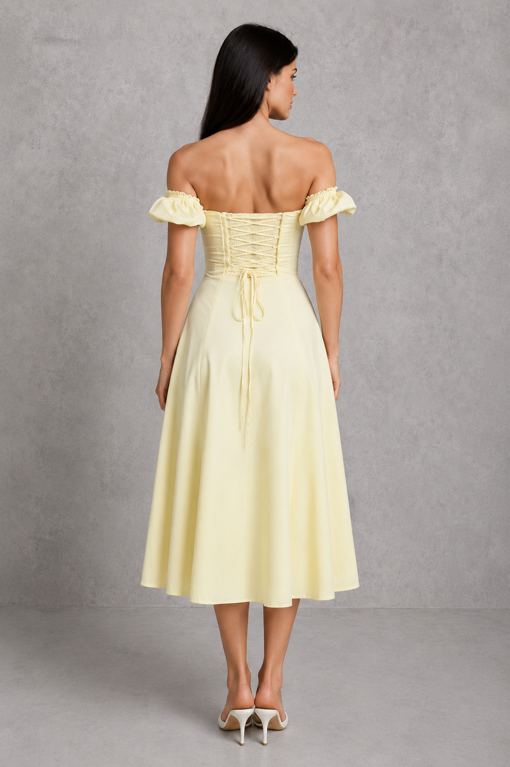 Woman wearing a light yellow off-shoulder dress against a gray background