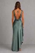 Woman wearing a green evening gown with a open back against a gray background