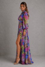 Woman wearing a colorful floral dress with a high slit on a gray background
