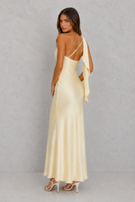 Woman wearing a long, light-colored dress with thin straps against a plain background