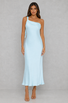 Woman wearing a light blue one-shoulder dress against a gray background