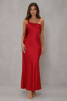 Woman wearing a red one-shoulder dress against a gray background