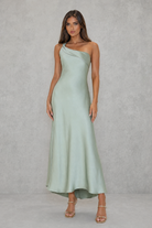 Woman wearing a light green one-shoulder dress against a plain background