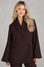 Women's oversized asymmetrical blazer with a relaxed fit, structured shoulder pads, asymmetrical front button fastening and side slits, ideal for smart-casual workwear and everyday layering.