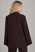 Women's oversized asymmetrical blazer with a relaxed fit, structured shoulder pads, asymmetrical front button fastening and side slits, ideal for smart-casual workwear and everyday layering.