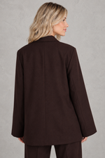 Women's oversized asymmetrical blazer with a relaxed fit, structured shoulder pads, asymmetrical front button fastening and side slits, ideal for smart-casual workwear and everyday layering.
