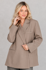 Women's oversized asymmetrical blazer with a relaxed fit, structured shoulder pads, asymmetrical front button fastening and side slits, ideal for smart-casual workwear and everyday layering.
