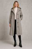 Women's oversized waterproof trench coat with a longline silhouette, adjustable drawstring hood, elasticated cuffs and lightweight water-repellent fabric, ideal for rainy weather and everyday wear.