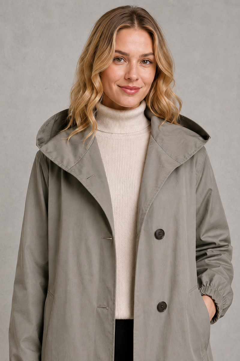 Women's oversized waterproof trench coat with a longline silhouette, adjustable drawstring hood, elasticated cuffs and lightweight water-repellent fabric, ideal for rainy weather and everyday wear.