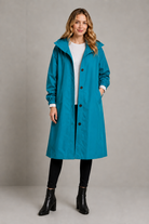 Women's oversized waterproof trench coat with a longline silhouette, adjustable drawstring hood, elasticated cuffs and lightweight water-repellent fabric, ideal for rainy weather and everyday wear.