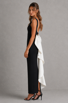 Woman wearing a black dress with a white overlay against a gray background