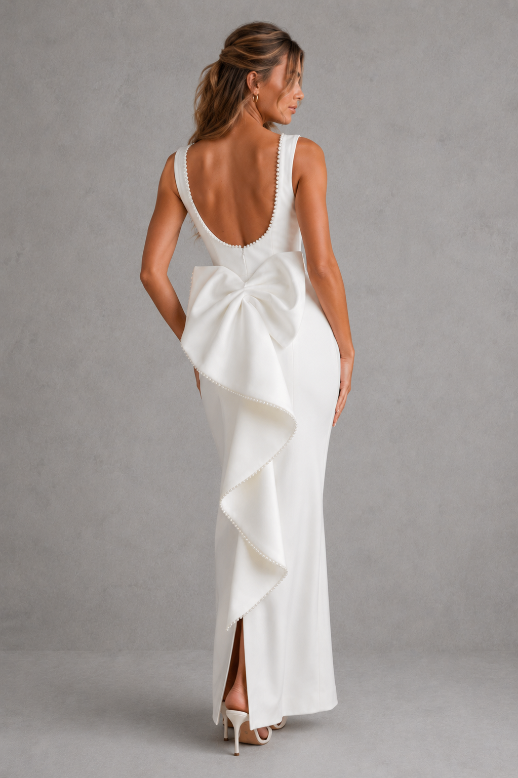 Woman wearing a white dress with a large bow detail on a gray background