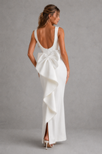 Woman wearing a white dress with a large bow detail on a gray background
