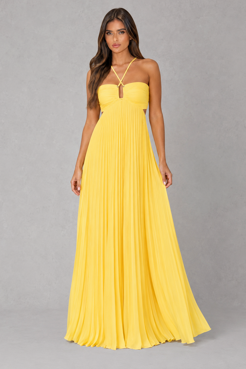 A woman modeling a bright yellow strapless maxi dress with a sweetheart neckline, thin crisscross halter straps, and a pleated skirt, set against a neutral gray studio background.