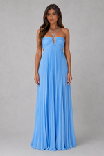 A woman modeling a light blue strapless maxi dress with a pleated skirt and a keyhole cutout at the bust, standing against a neutral gray studio background.