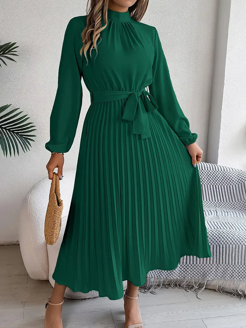 Woman wearing a green dress in a room with a white wall and striped rug.
