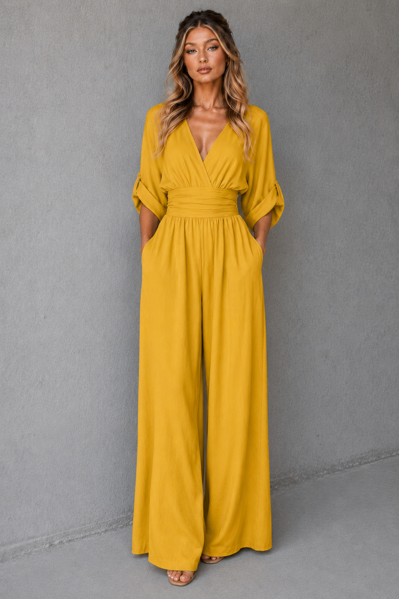 Woman wearing a mustard yellow jumpsuit against a gray background