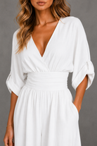 White dress with a plunging neckline and long sleeves on a gray background