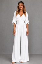 Woman wearing a white jumpsuit against a gray background
