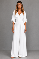 Woman wearing a white jumpsuit against a gray background