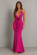 Woman wearing a vibrant pink dress with floral details against a plain background