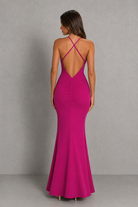 Woman wearing a pink evening gown with a backless design against a gray background