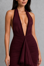 Maroon halter neck dress on a model against a gray background