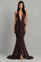 Woman wearing a deep-neck, brown evening gown against a gray background