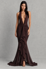 Woman wearing a deep-neck, brown evening gown against a gray background