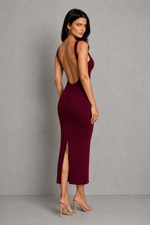 Woman wearing a burgundy dress with an open back and slit on a gray background