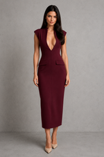 Woman wearing a burgundy dress with a plunging neckline against a gray background
