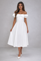 Woman wearing a white off-shoulder dress on a gray background