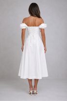 Woman wearing a white off-shoulder dress on a gray background