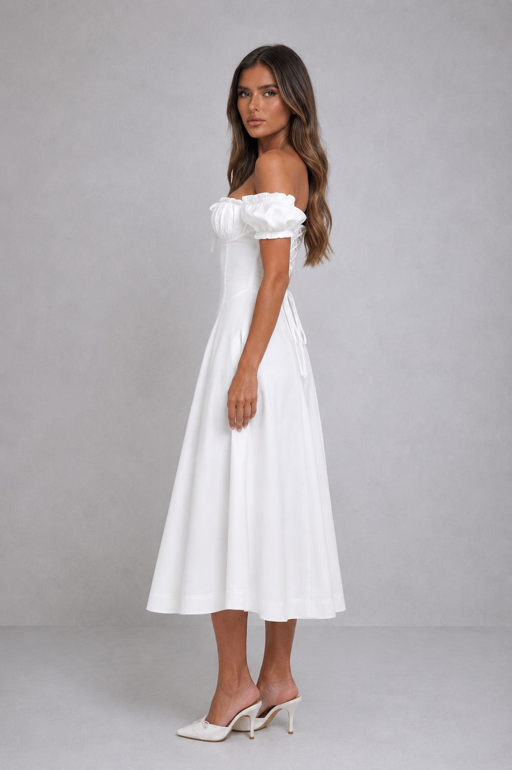 Woman wearing a white off-shoulder dress against a gray background