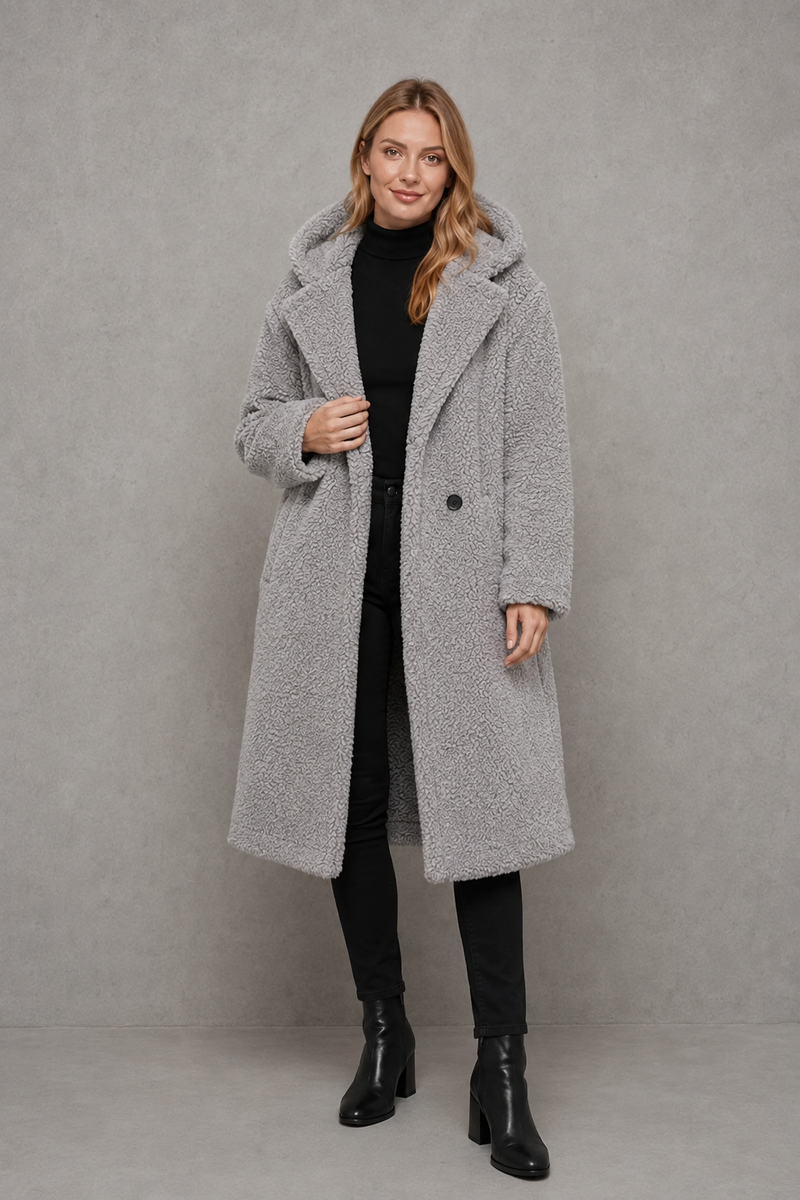Women's quilted longline coat with a padded design, protective hood, deep side pockets and a relaxed fit, offering warm, lightweight comfort for autumn and winter wear.