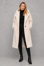 Women's quilted longline coat with a padded design, protective hood, deep side pockets and a relaxed fit, offering warm, lightweight comfort for autumn and winter wear.