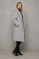 Women's quilted longline coat with a padded design, protective hood, deep side pockets and a relaxed fit, offering warm, lightweight comfort for autumn and winter wear.