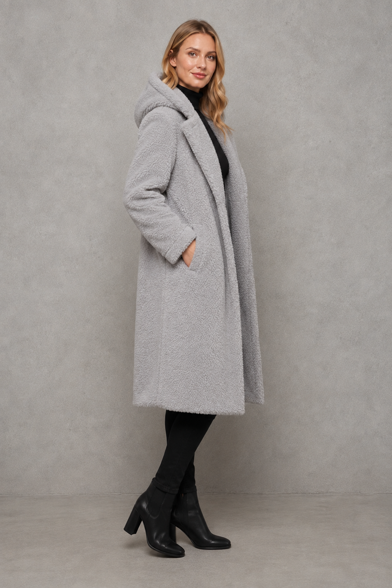 Women's quilted longline coat with a padded design, protective hood, deep side pockets and a relaxed fit, offering warm, lightweight comfort for autumn and winter wear.