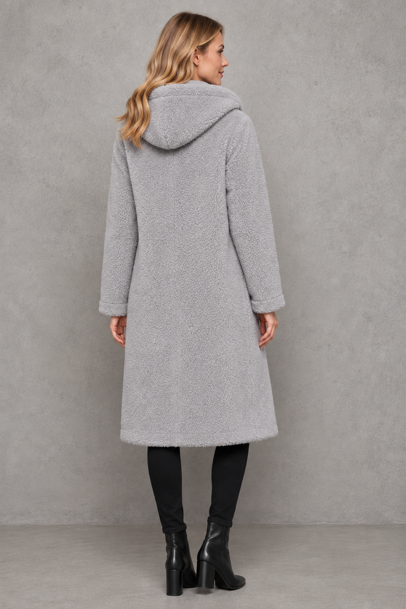 Women's quilted longline coat with a padded design, protective hood, deep side pockets and a relaxed fit, offering warm, lightweight comfort for autumn and winter wear.