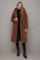 Women's quilted longline coat with a padded design, protective hood, deep side pockets and a relaxed fit, offering warm, lightweight comfort for autumn and winter wear.