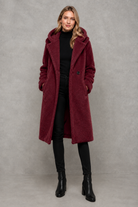 Women's quilted longline coat with a padded design, protective hood, deep side pockets and a relaxed fit, offering warm, lightweight comfort for autumn and winter wear.