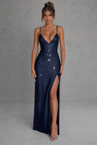 Navy blue sequin gown with a deep neckline and high slit on a gray background