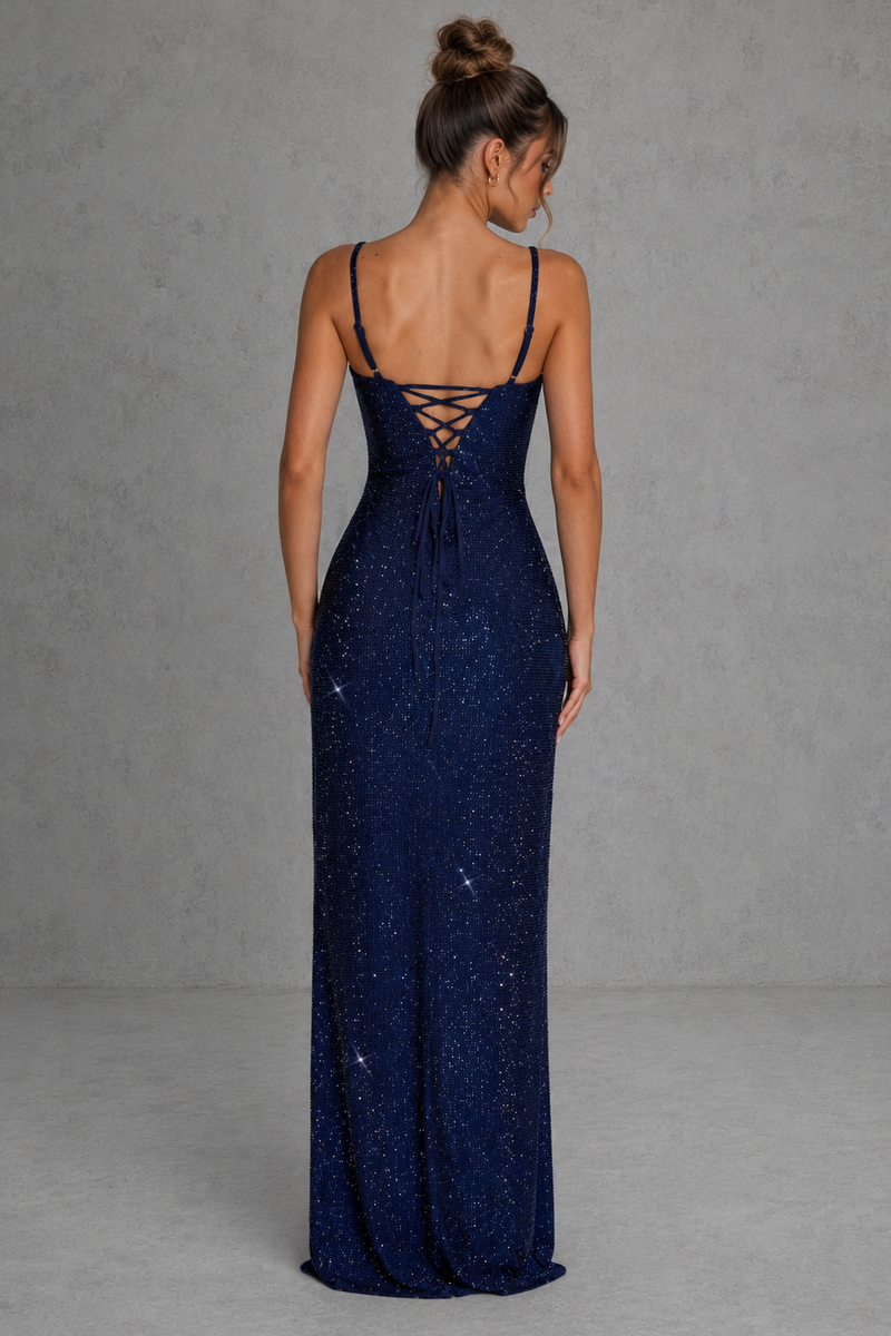 Woman wearing a navy blue evening gown with a lace-up back against a gray background