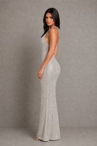 Woman wearing a silver beaded evening gown against a gray background