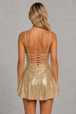 Gold sequin dress with open back worn by a model on a gray background