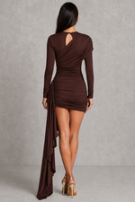 Woman wearing a brown dress with a draped design on a plain background