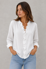 Woman wearing a white blouse and blue jeans against a gray background