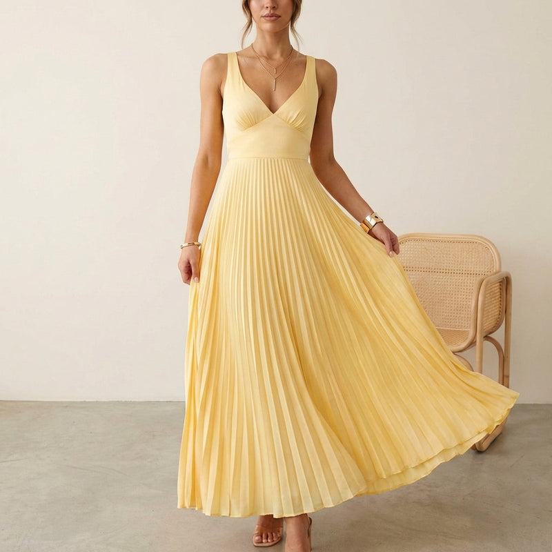 Woman wearing a yellow pleated dress in a minimalistic setting